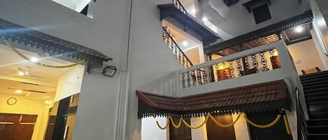 Un edificio de varios pisos con un patio central, una escalera y un comedor con sillas y mesas.