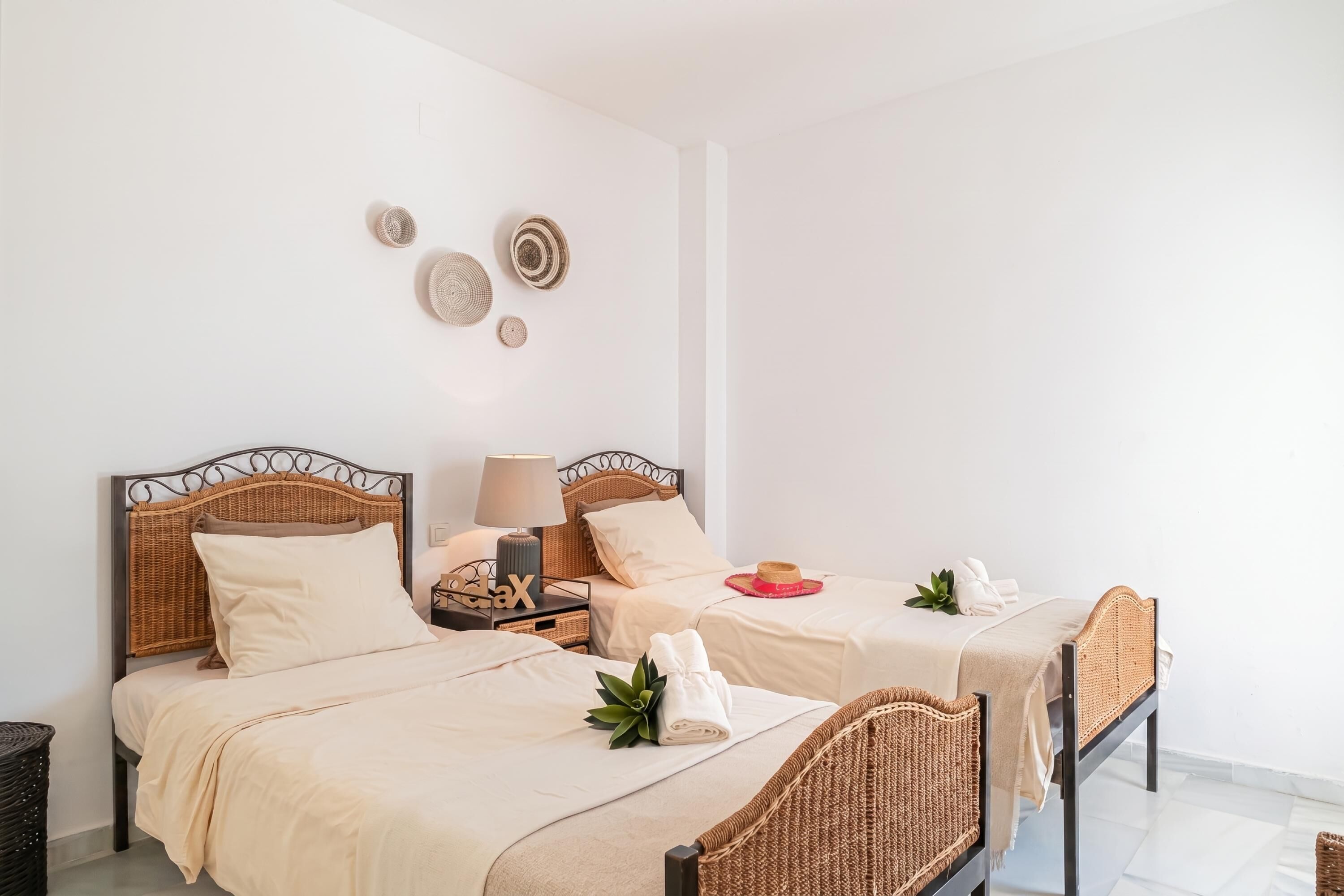 A hotel room with two beds, a nightstand with a lamp, and decorative wall art.