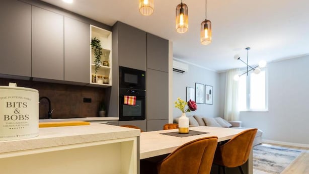 A modern kitchen with grey cabinets, a built-in oven, and pendant lighting. - Cultural Haven Central Two Bedroom Apartment in Zadar With City Views (Zadar)