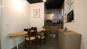 A compact kitchen with a microwave, stove, and sink. There is a dining area with a table and chairs. - Quiet Studio in Zadars Old Town (Zadar)