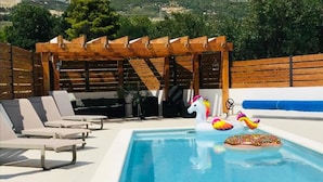 Una piscina con sillas de descanso y una pérgola de madera.