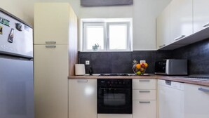 Cocina moderna con refrigerador, horno, microondas y una ventana sobre el fregadero.