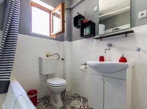 A compact bathroom with a toilet, sink, and window.