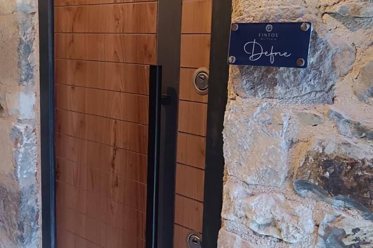 A wooden door with a black handle and a sign reading "Detmold" on a stone wall.