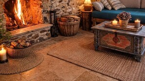 Ein rustikaler Raum mit Kamin aus Stein, einer Couch und einem Couchtisch.