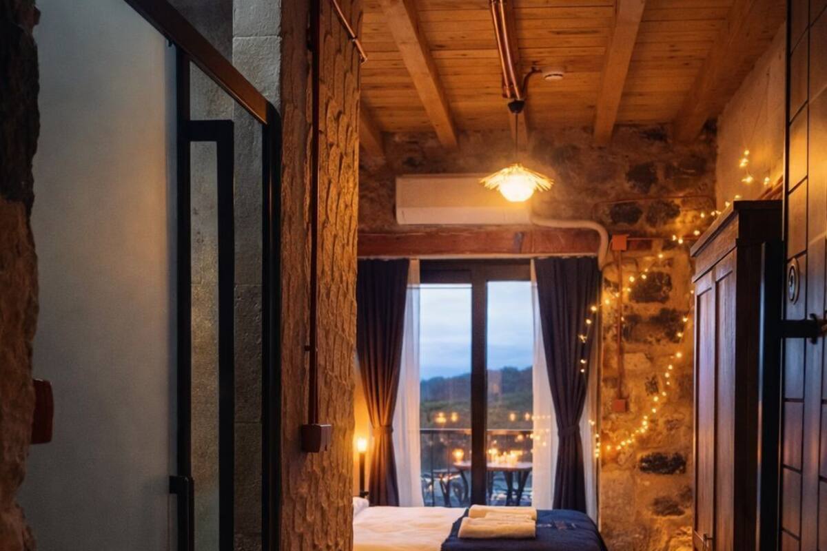 A narrow hallway leading to a bedroom with a large window, a bed, and a view of the outside.