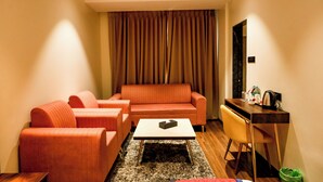 A modern living room with a sofa, a coffee table, and a desk with a chair. - Spree Manor Hotel (Chhatrapati Sambhajinagar)