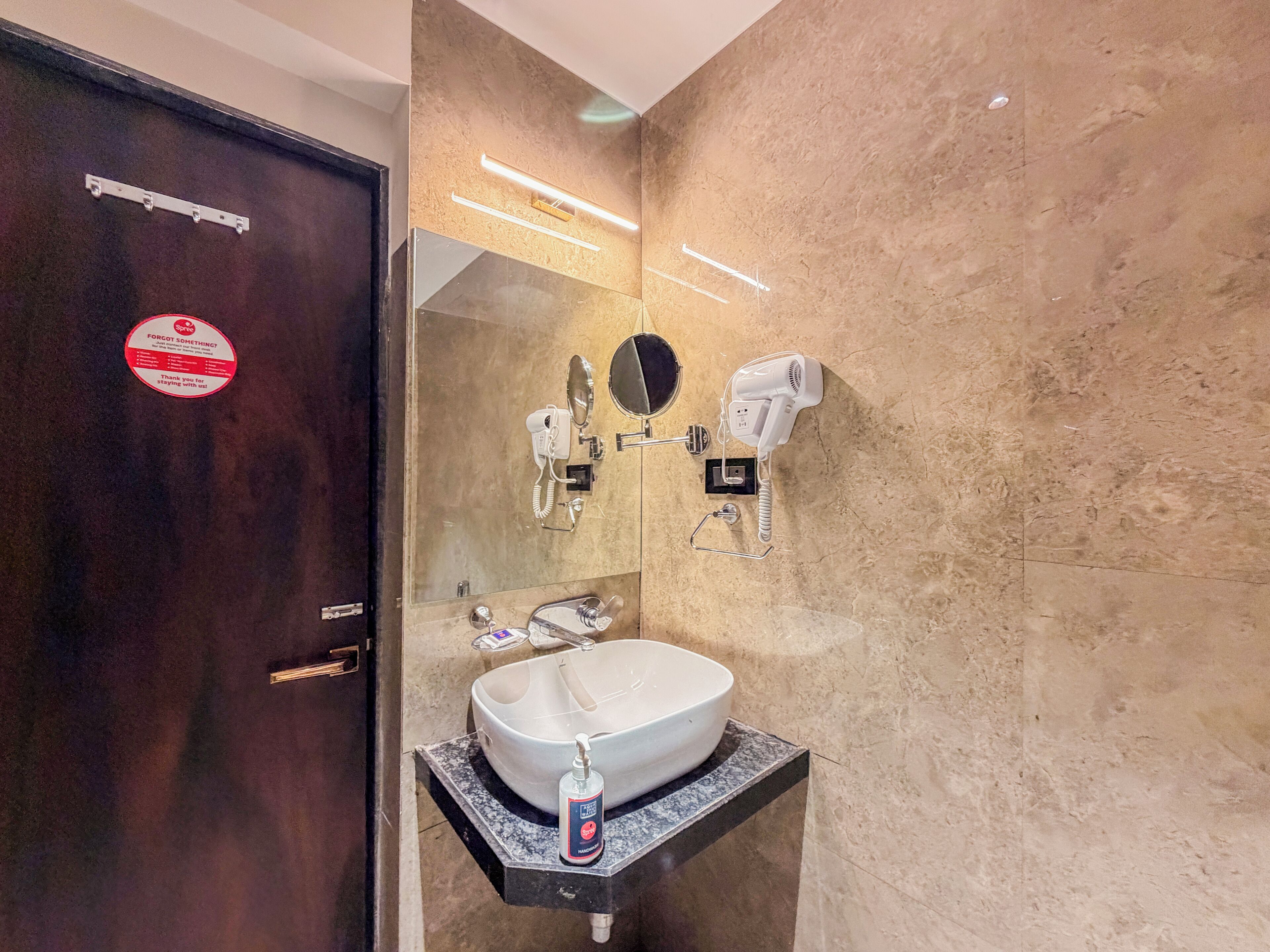 A bathroom with a sink, mirror, hairdryer, and phone.