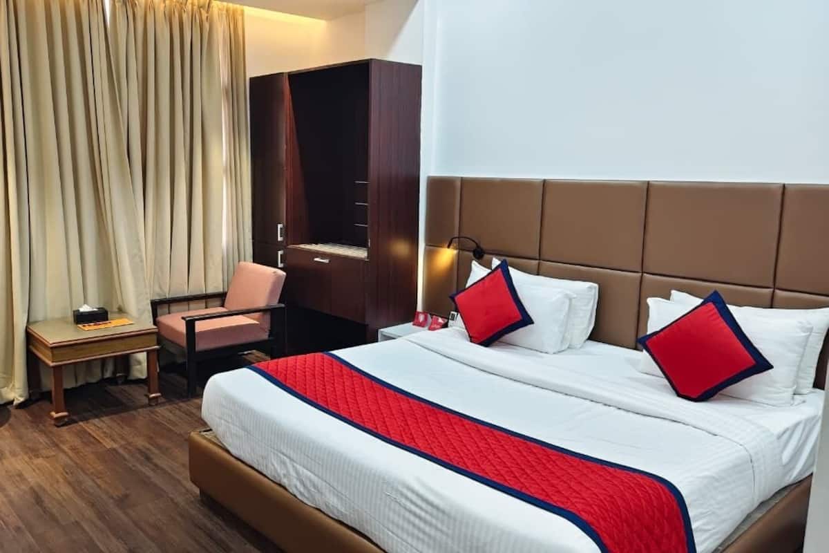 A hotel room with a bed, a desk, a chair, a wardrobe, and a curtain.