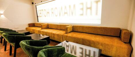A seating area with a large screen displaying "THE WARMING ROOM" and a sofa with a sign "THE WARMING ROOM" in front.