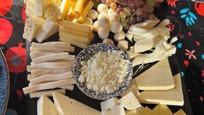 Une planche de charcuterie accompagnée de différents fromages, de raisins et de noix.