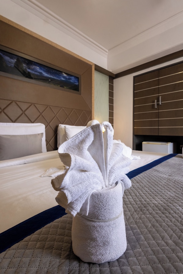 Una habitación de hotel con cama, una decoración de toallas, un cuadro en la pared y un armario.