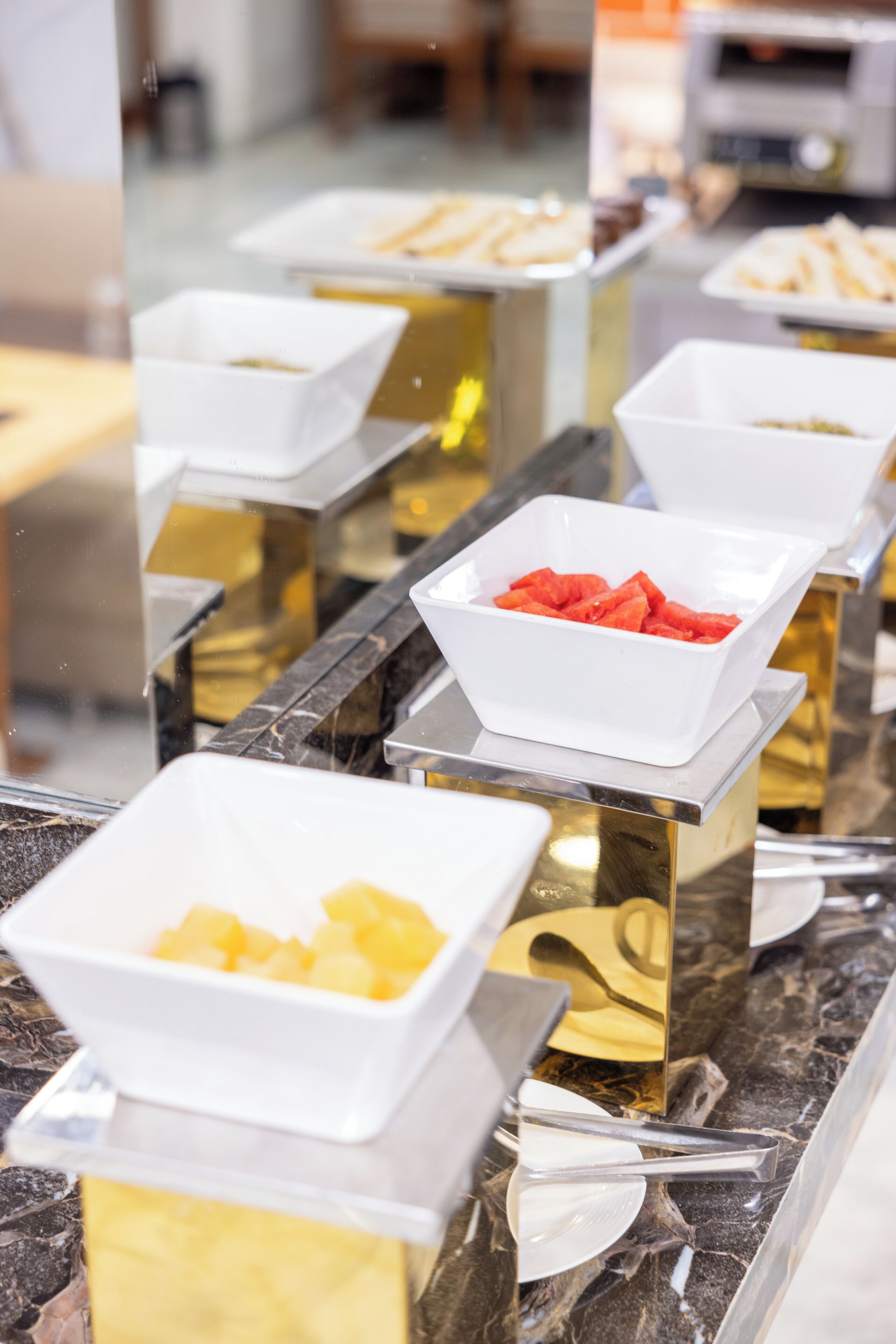 Een buffetopstelling met witte kommen gevuld met fruit en een lepel.