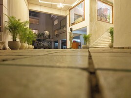 Un amplio vestíbulo con diseño moderno, que incluye una escalera grande, plantas en macetas y una estatua.