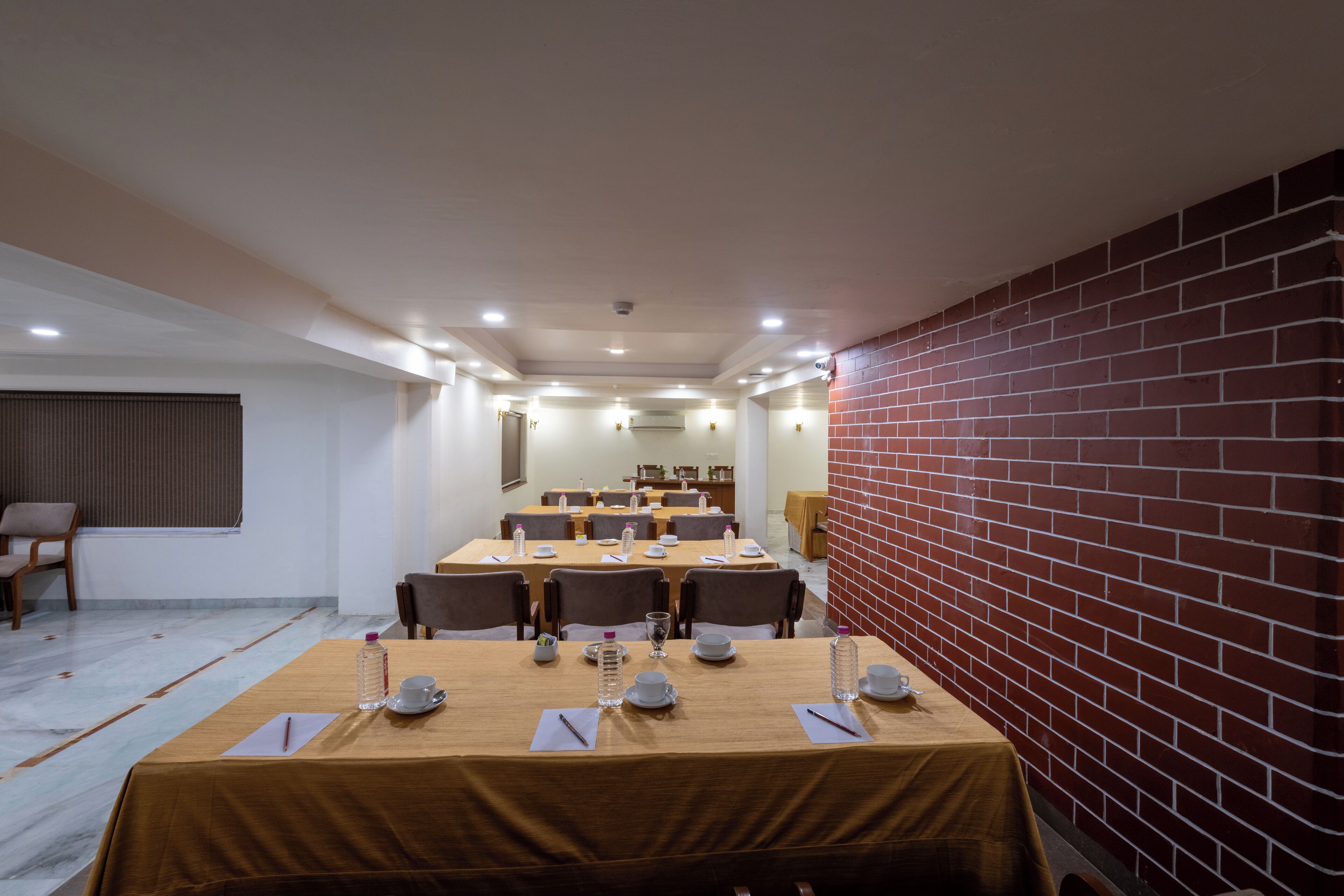 A conference room with multiple tables, chairs, and a brick wall.