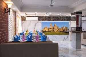 Un vestíbulo de hotel con piso de mármol, una sala de estar con vista a un edificio imponente y una pared decorativa con un mural.