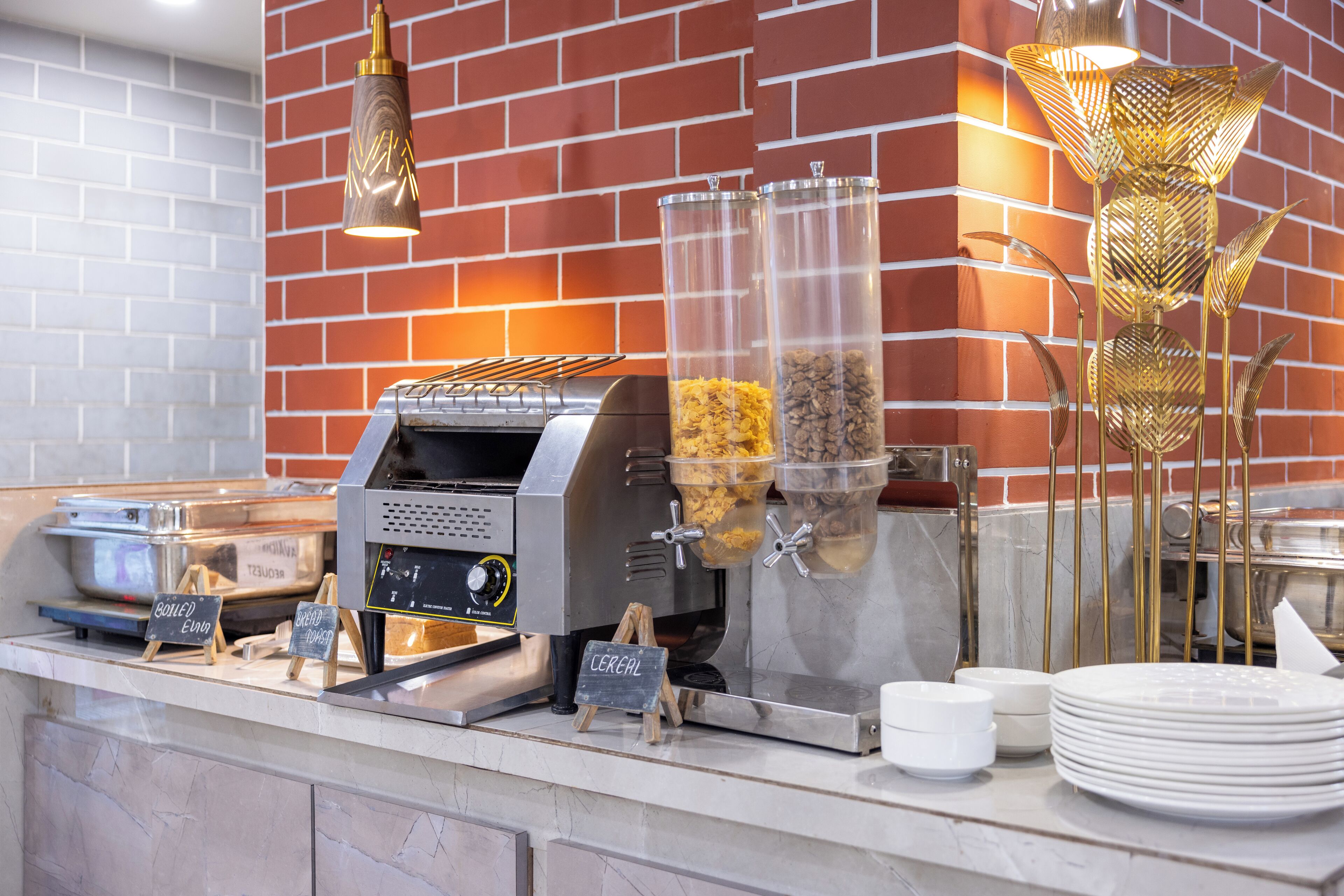 A breakfast bar with a coffee machine, cereal dispensers, and a stack of white plates.