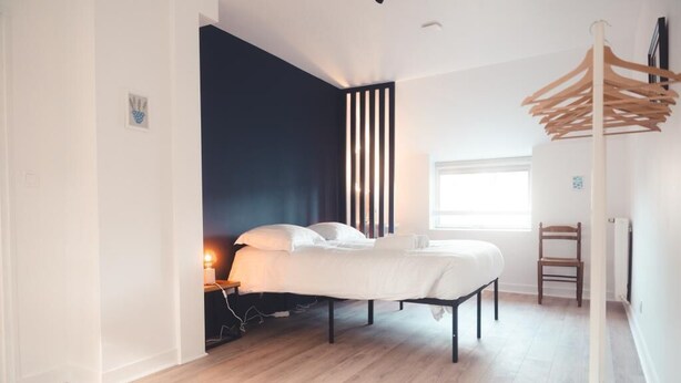 Un dormitorio moderno con cama, mesita de noche y perchero.