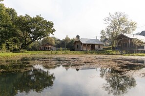 A lakeside property with wooden cabins, a dock, and a reflection in the water. - Cozy Cabins in Vencimont (Vencimont)