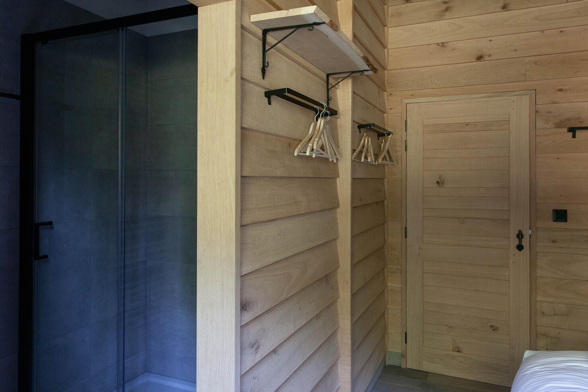 A room with wooden paneling, a sliding glass door, and a bed with a white comforter.