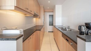 Una cocina moderna con armarios de madera, encimera negra y electrodomésticos de acero inoxidable.