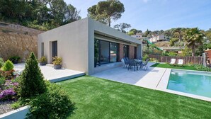 A modern house with a swimming pool, a patio with outdoor furniture, and a well-maintained garden. - Villa in Lloret de Mar with Private Pool (Vidreres)