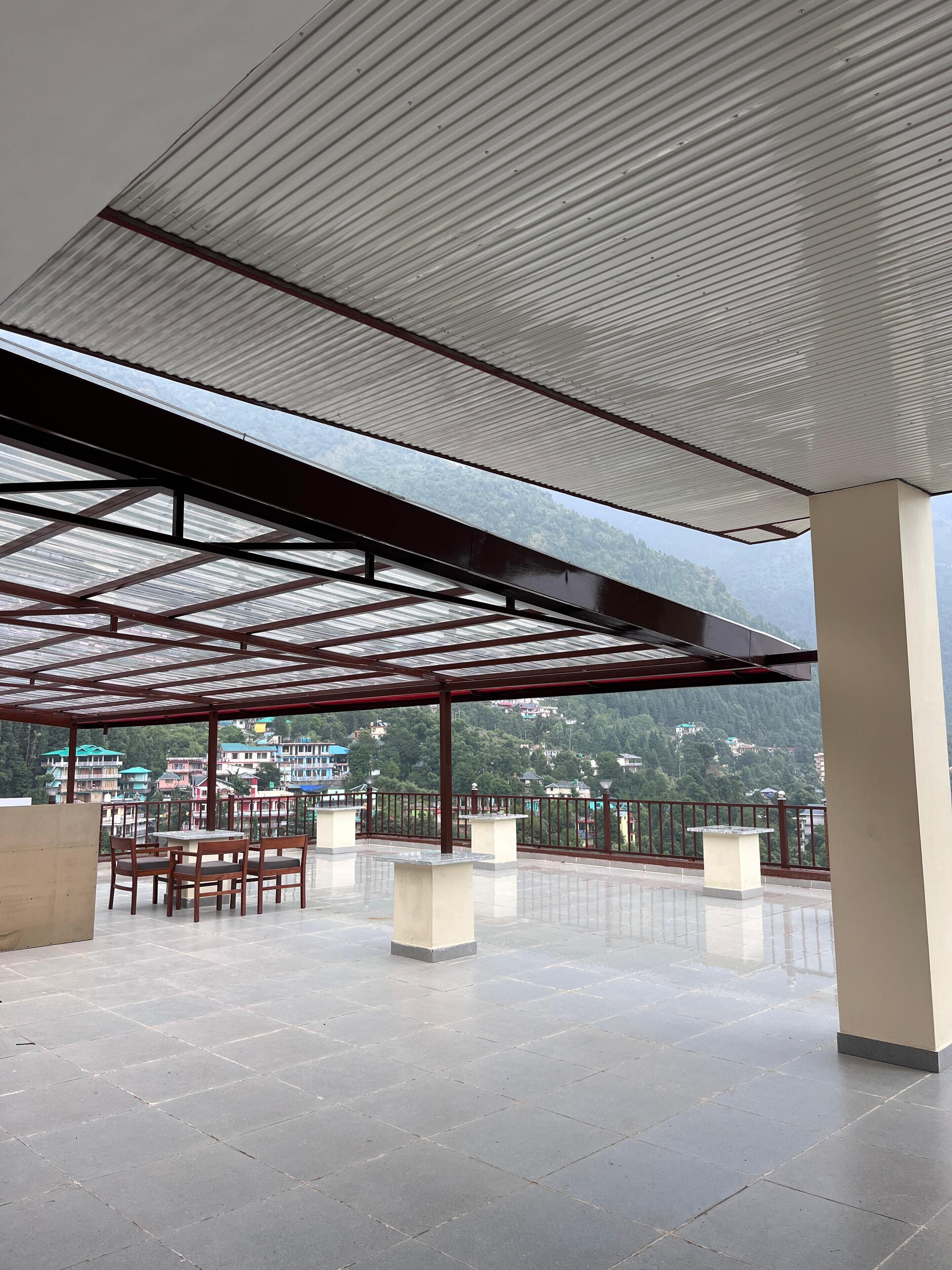 A covered terrace with a view of a mountainous landscape.