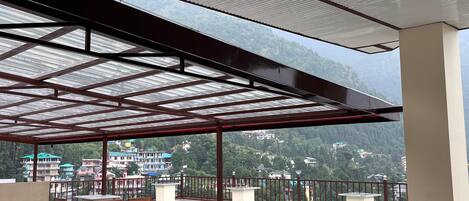 A covered terrace with a view of a mountainous landscape.