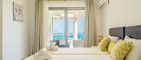 A hotel room with a large bed, a view of the sea, and a balcony.