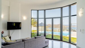 Un salon moderne doté d’une grande fenêtre, d’un téléviseur à écran plat et d’un canapé gris.
