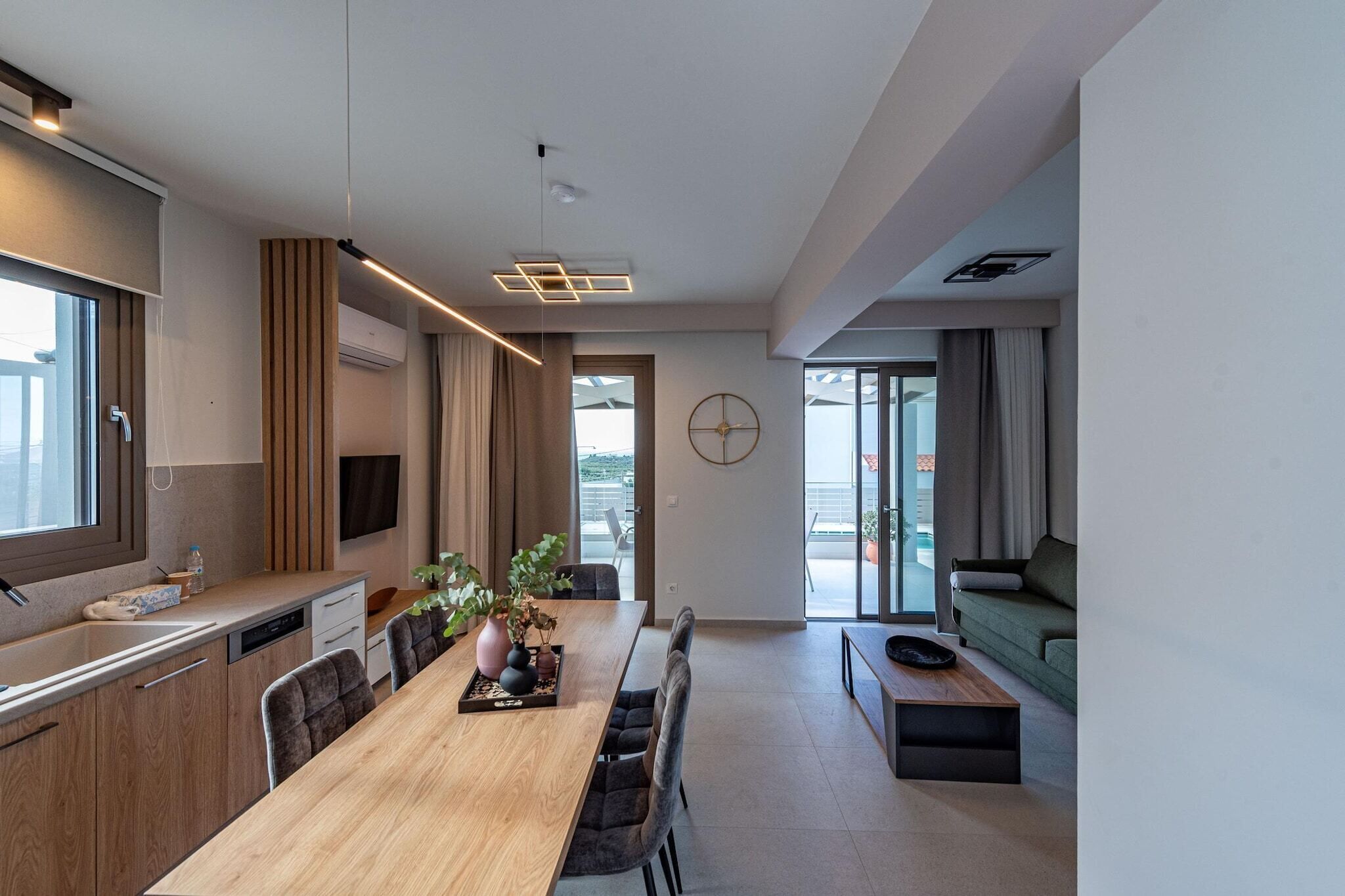 A modern kitchen with a wooden countertop, a built-in dishwasher, and a dining area with a long table and chairs.