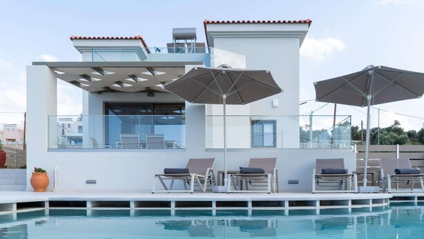 Een modern zwembadgedeelte met ligbedden en parasols, een glazen balustrade en een helder uitzicht op het omliggende landschap.