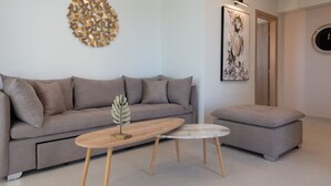 Een moderne woonkamer met een grijze bank, een ronde salontafel en een grijze poef.