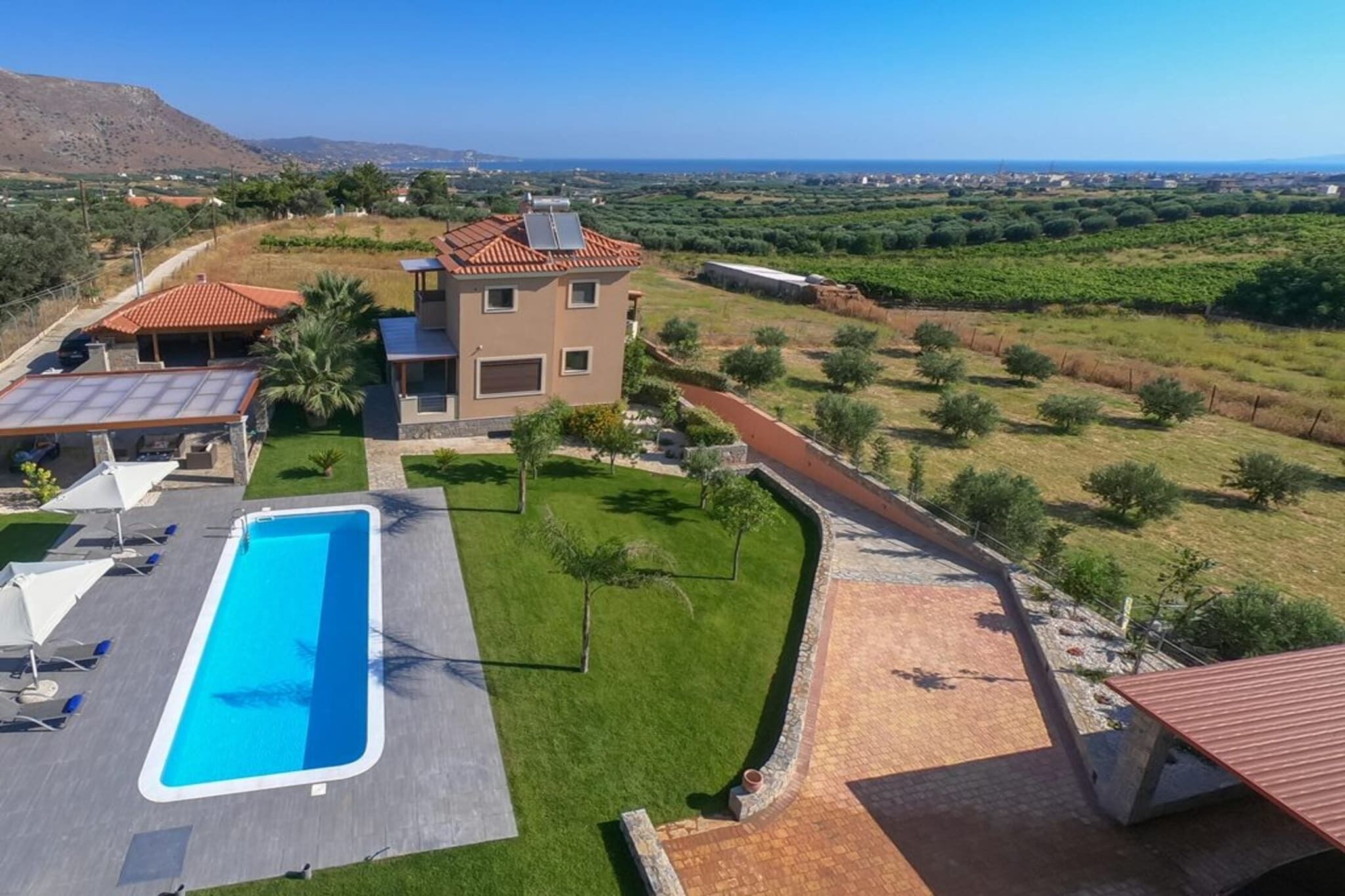 Una villa moderna con piscina, cancha de tenis y vistas al mar y al campo circundante.