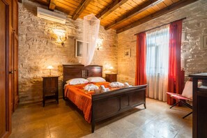 Camera con pareti in pietra, un letto di legno, due comodini e una sedia.