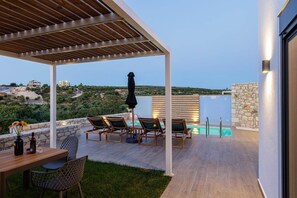 Un espacio al aire libre techado con piscina, sillas de descanso y una mesa con bebidas.