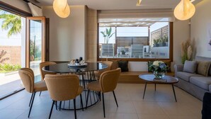 Una sala de estar moderna con una mesa de comedor redonda, asientos cómodos y ventanas amplias con vistas al exterior.