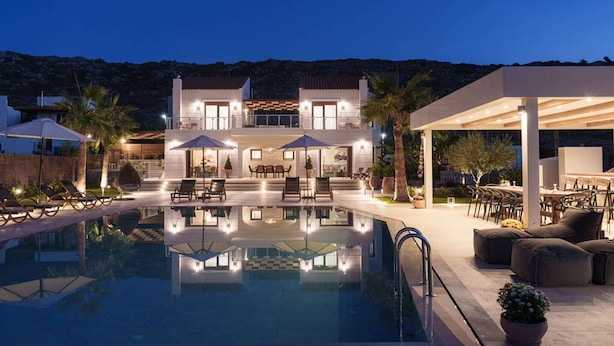 Une villa moderne dotée d’une piscine, d’un espace salon extérieur et d’un patio couvert.