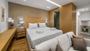 A modern bedroom with a large bed, bedside tables, a wooden bench, and a small potted plant. - Villa in Gournes with Private Pool & Sea Views (Heraklion)