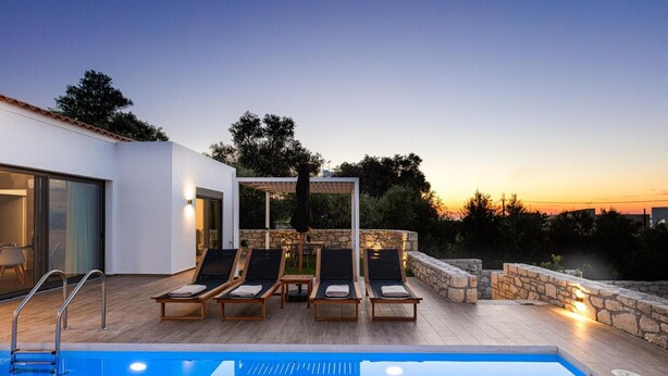 A modern outdoor pool area with lounge chairs and a stone wall.