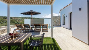 A covered outdoor dining area with a table, chairs, and an umbrella.