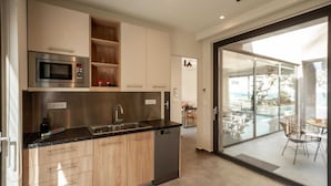 A modern kitchen with a built-in microwave, stainless steel appliances, and a dishwasher. There is a large sliding glass door leading to an outdoor area with a pool and chairs.