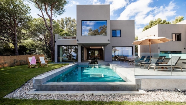 A modern house with a swimming pool, outdoor seating, and a large window overlooking the yard.