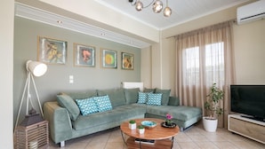 A living room with a sectional sofa, a round coffee table, a television, and a potted plant.