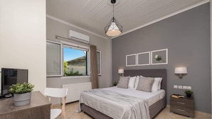 A modern bedroom with a large bed, bedside lamps, a desk with a computer, and a window with a view of the outdoors.