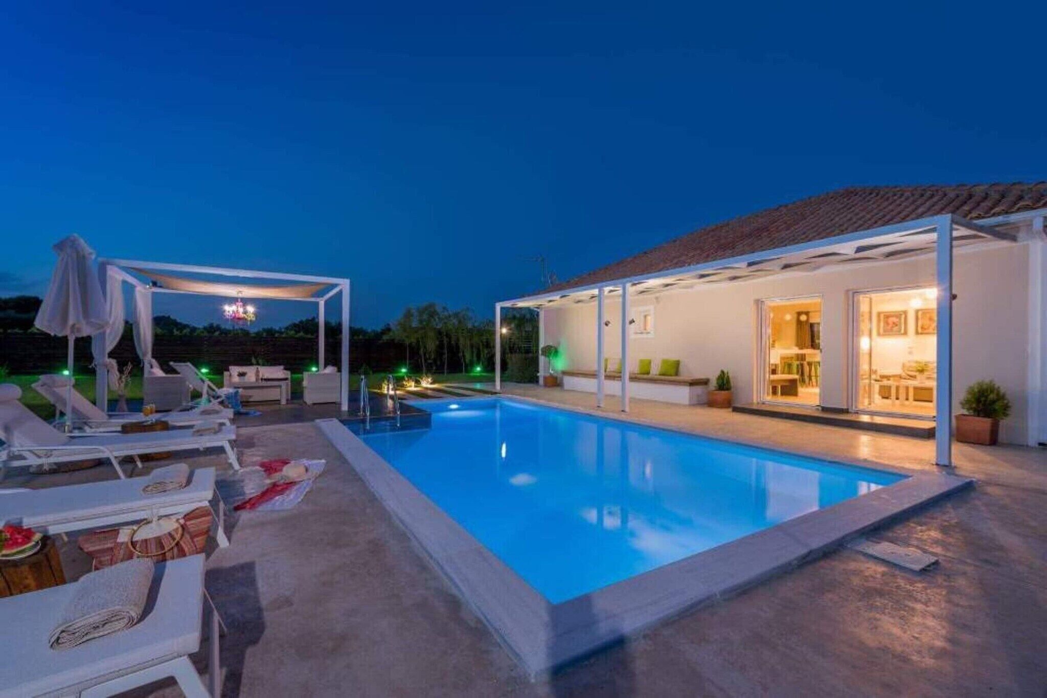 Una piscina con sillas de descanso y una zona de estar cubierta.