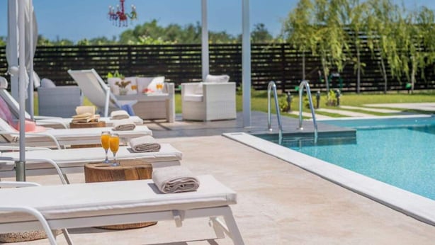 A poolside area with lounge chairs, a canopy, and a pool.