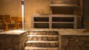 Una escalera de piedra conduce a una zona de chimenea con bancos y una pared de piedra.