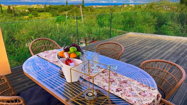Un espacio de comedor al aire libre con una mesa para dos, rodeado de sillas de mimbre y vistas a un paisaje exuberante.