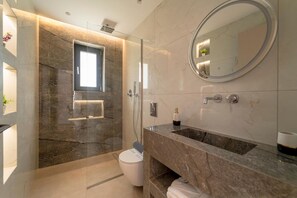 A modern bathroom with a marble vanity, a round mirror, and a glass-enclosed shower area.